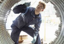 Mann prüft großes elektrisches Bauteil von Innen